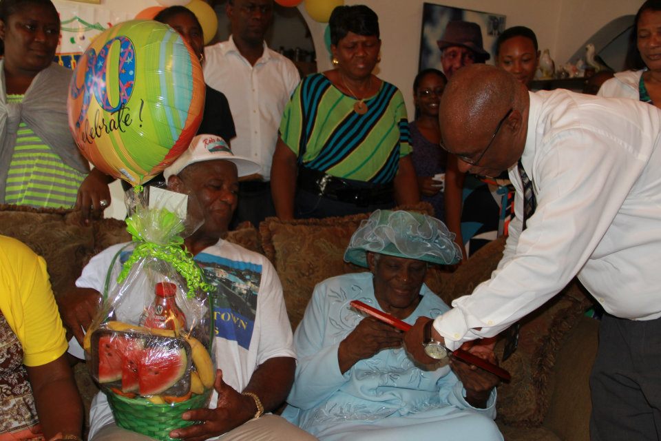 Premier of Nevis, Hon. Joseph Parry giving gifts to Mrs. Rosalie Martin on her 90th Birthday